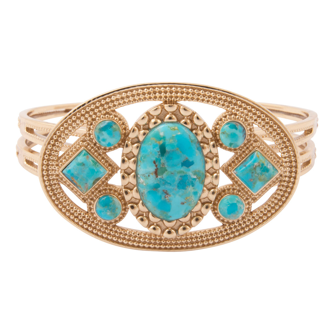 A gold-plated oval cuff ring featuring a central turquoise-colored stone and smaller matching stones, set against a plain white background.