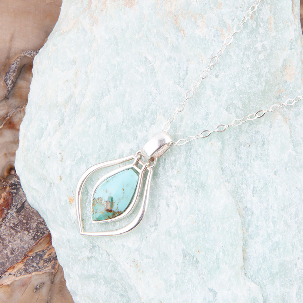 Silver necklace with a turquoise pendant on a textured stone background