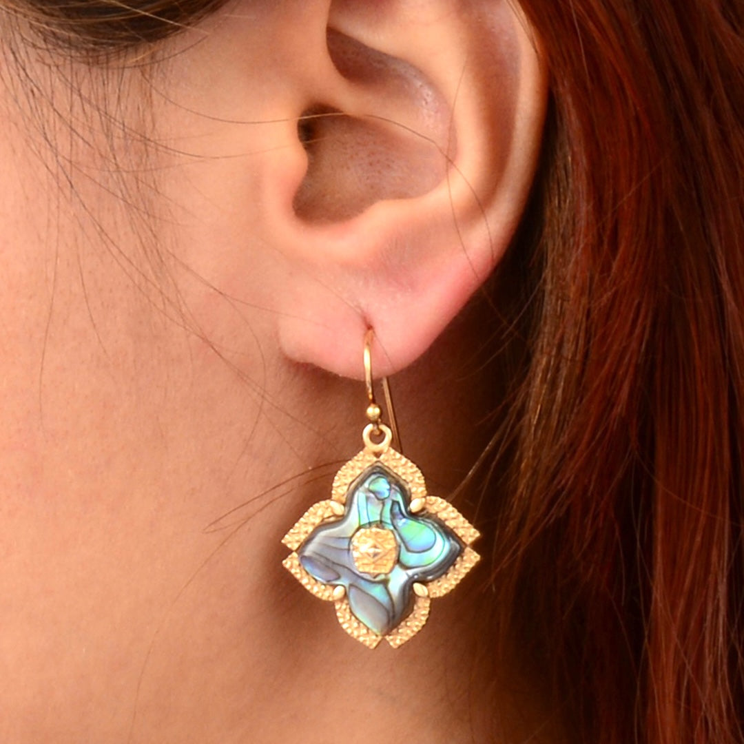 Close-up of an ear wearing a decorative earring with a blue and gold design.