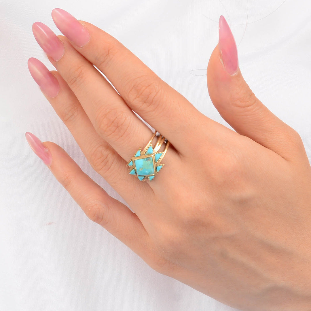 Hand wearing a turquoise ring on a white background