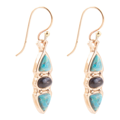 A pair of gold drop earrings featuring light blue turquoise stones and a central dark gray stone, shown on a plain white background.