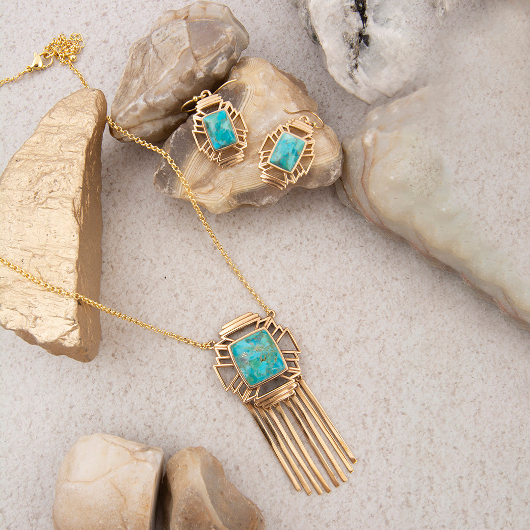 Gold necklace with turquoise stones on a stone surface