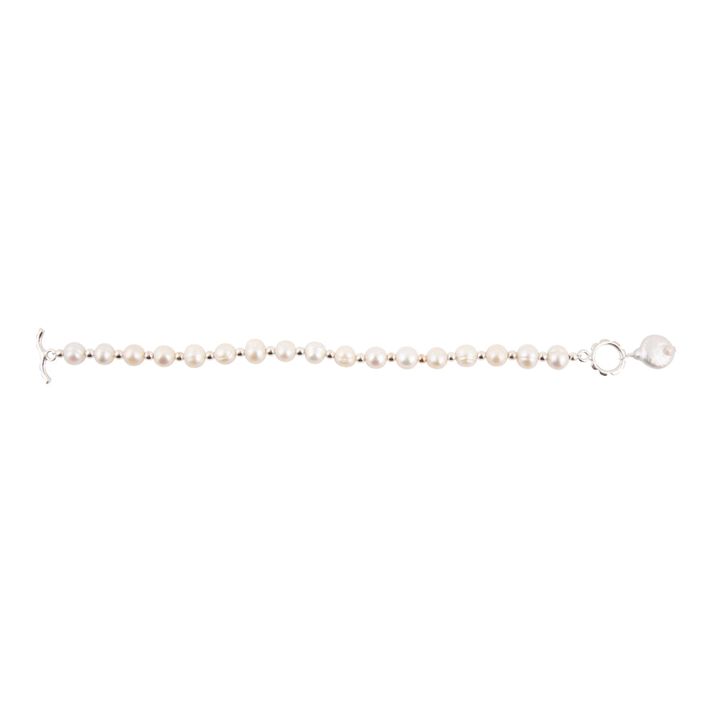 A delicate bracelet featuring small, round white pearls strung on a silver-toned metal chain with a lobster clasp, shown against a plain white background.