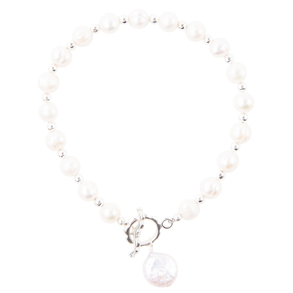 A beaded bracelet featuring white freshwater pearls separated by small silver spacer beads, finished with a silver toggle clasp and a dangling round white pearl charm.