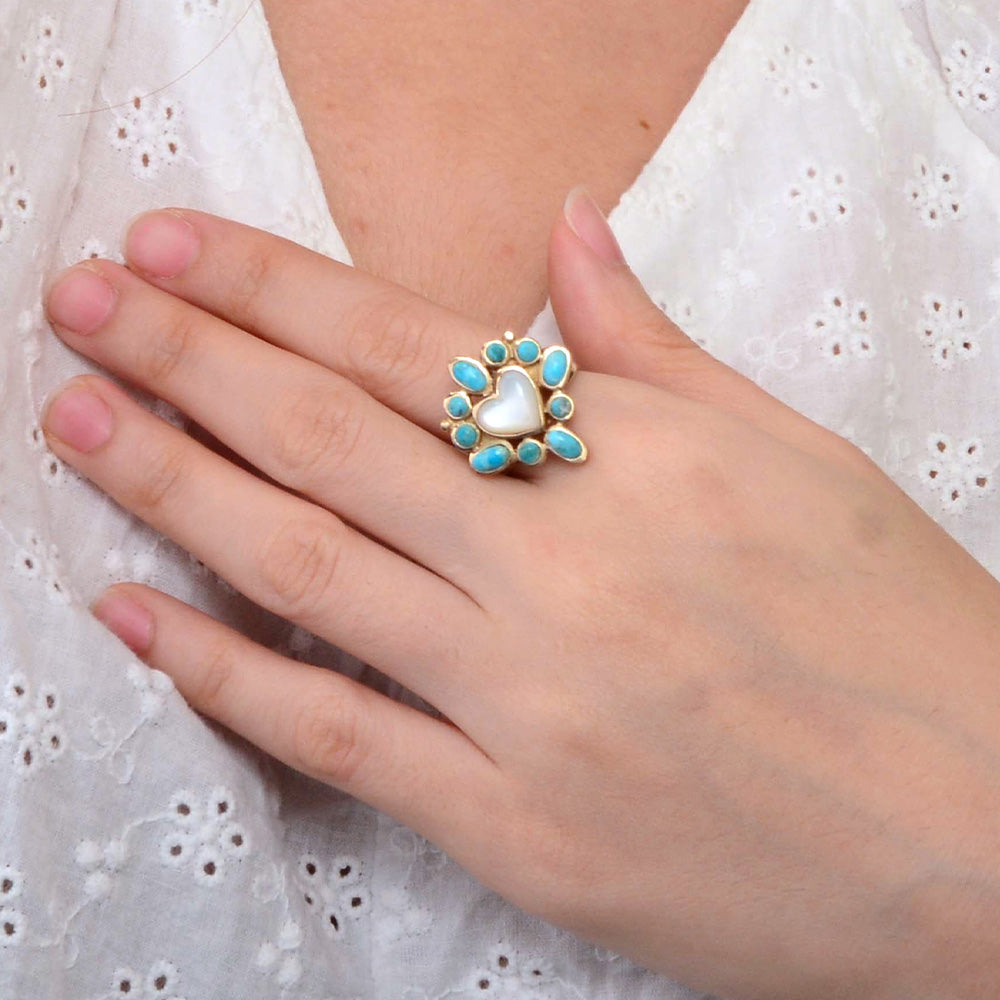 Hand wearing a ring with turquoise stones on a white lace background