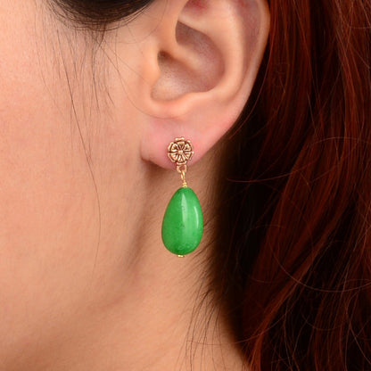 Green teardrop earring worn by a person with red hair.