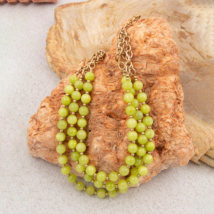 Green beaded necklace on a textured stone surface
