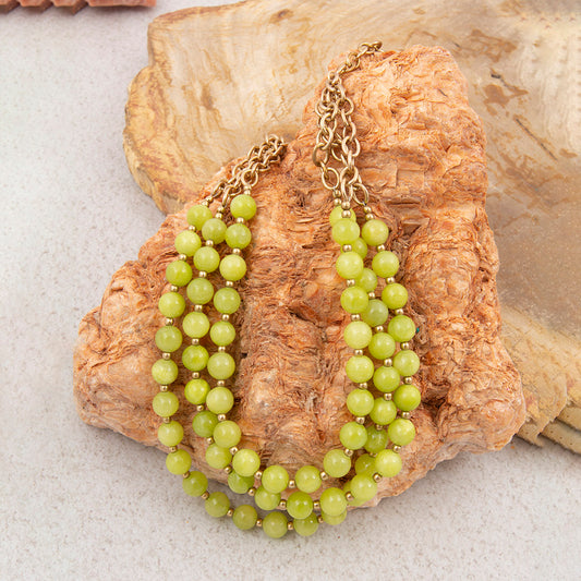 Green beaded necklace on a textured stone surface