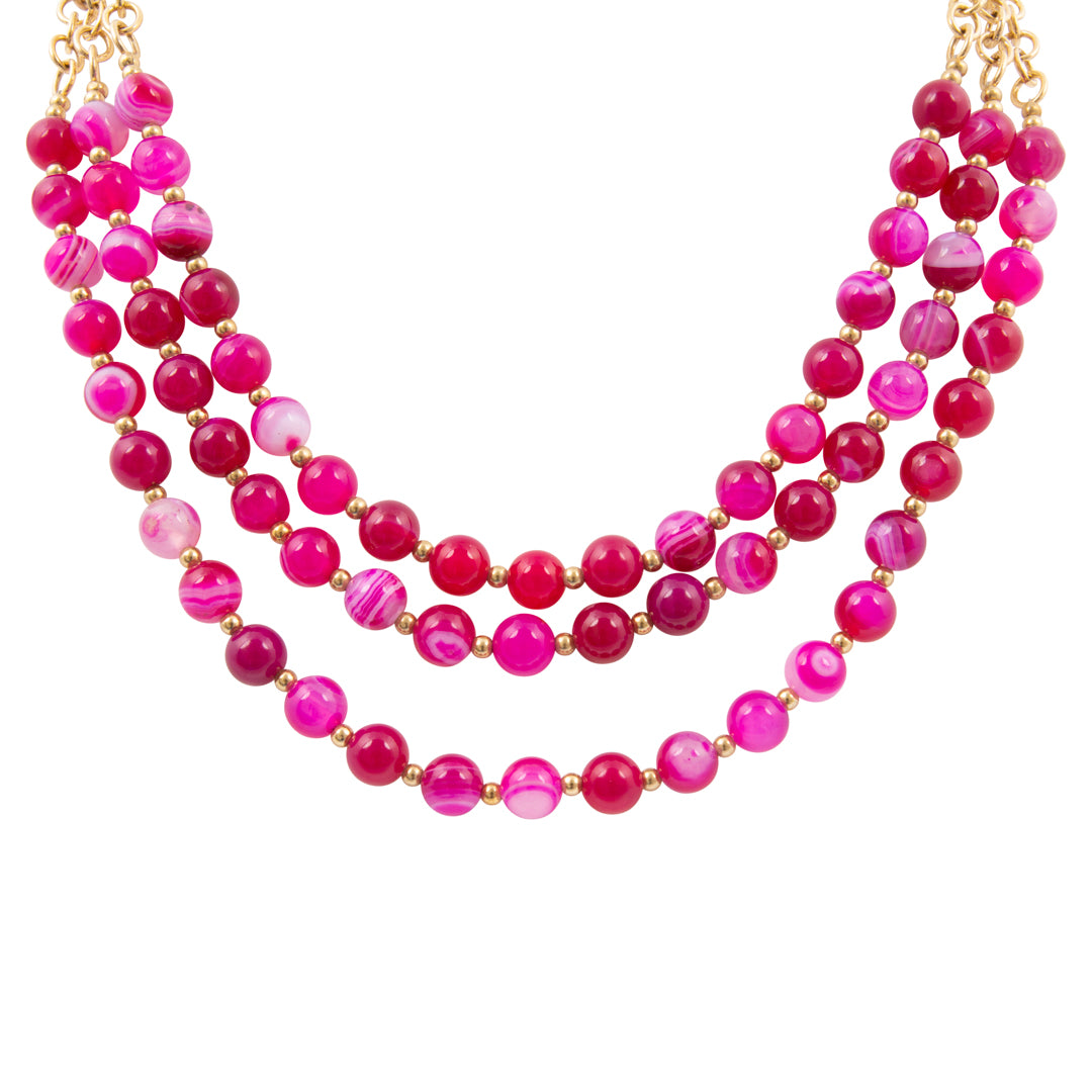 Multistrand pink beaded necklace with gold accents on a white background