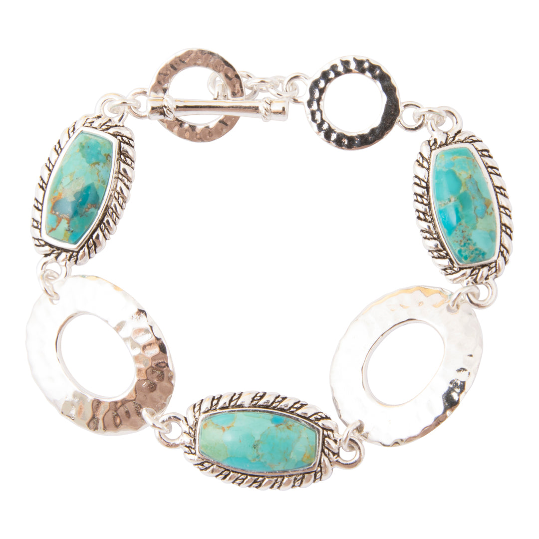 A sterling silver bracelet featuring five oval turquoise cabochon stones set in textured bezel settings, with three open oval links and a toggle clasp on a plain white background.
