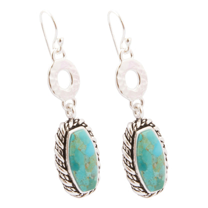 A pair of sterling silver dangle earrings featuring oval turquoise stone pendants with textured silver bezels and hammered silver circular links, shown on a plain white background.