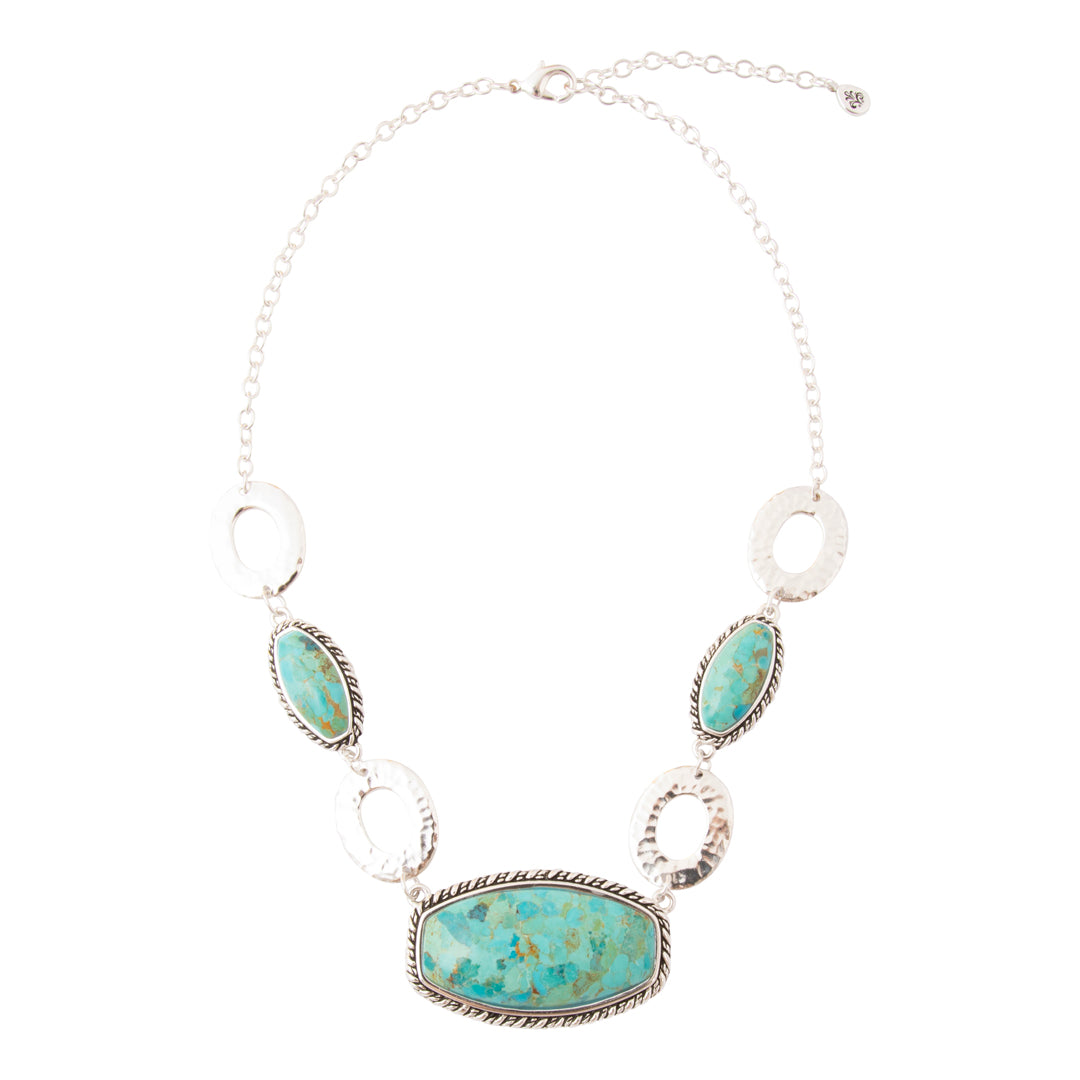 A silver statement necklace featuring a large oval turquoise stone centerpiece, three smaller matching turquoise stones, and three textured silver oval links, displayed on a clean white background.
