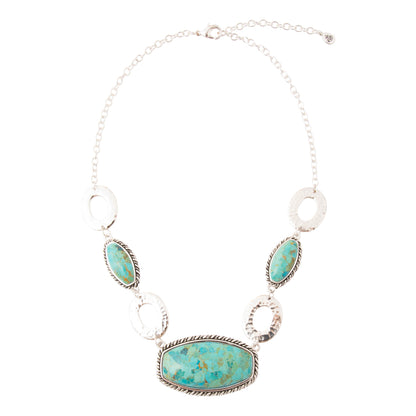 A silver statement necklace featuring a large oval turquoise stone centerpiece, three smaller matching turquoise stones, and three textured silver oval links, displayed on a clean white background.