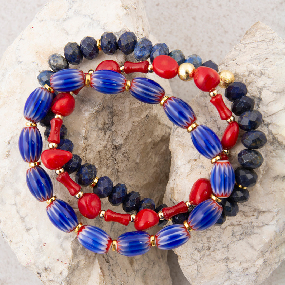 Beaded bracelet with blue, red, and gold beads on a textured stone surface
