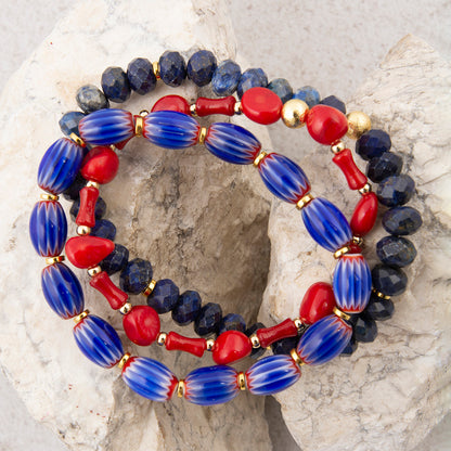 Beaded bracelet with blue, red, and gold beads on a textured stone surface