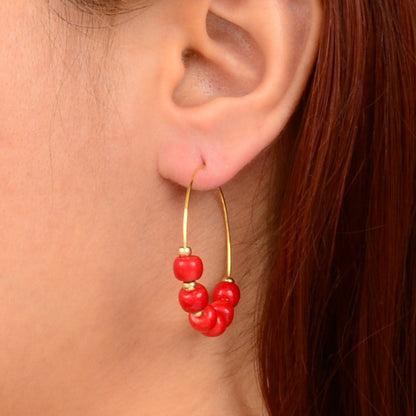 Red berry earrings on a person's ear with a neutral background