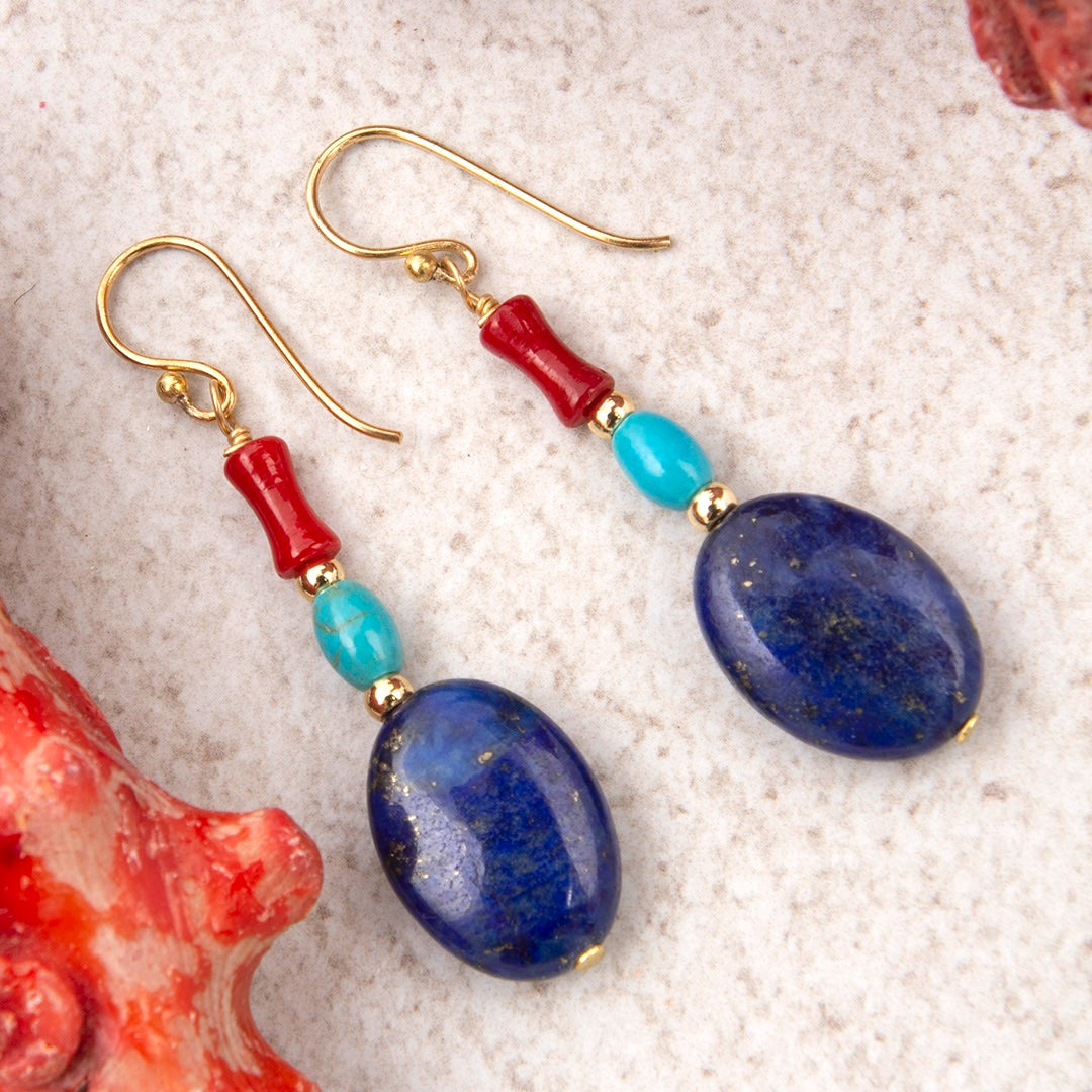 Pair of earrings with blue and red beads on a textured surface