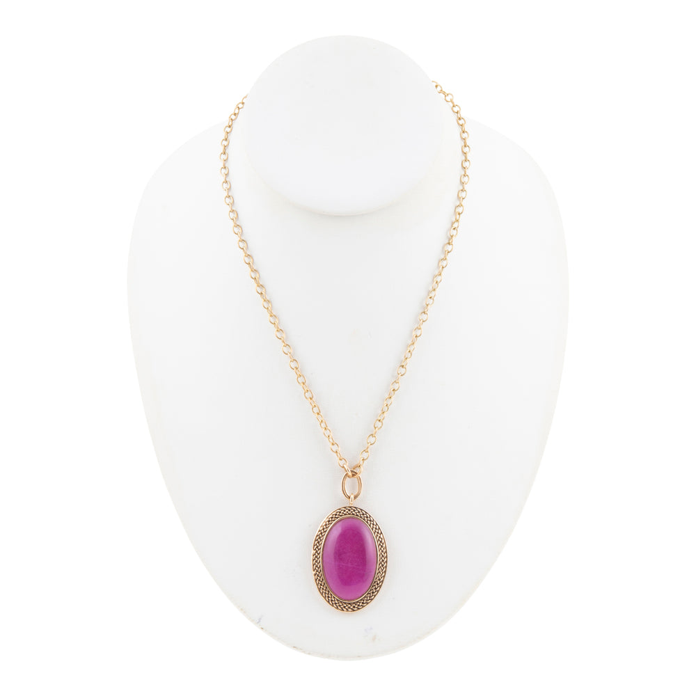 A gold chain necklace with an oval purple cabochon stone pendant, displayed on a white jewelry bust against a white background.