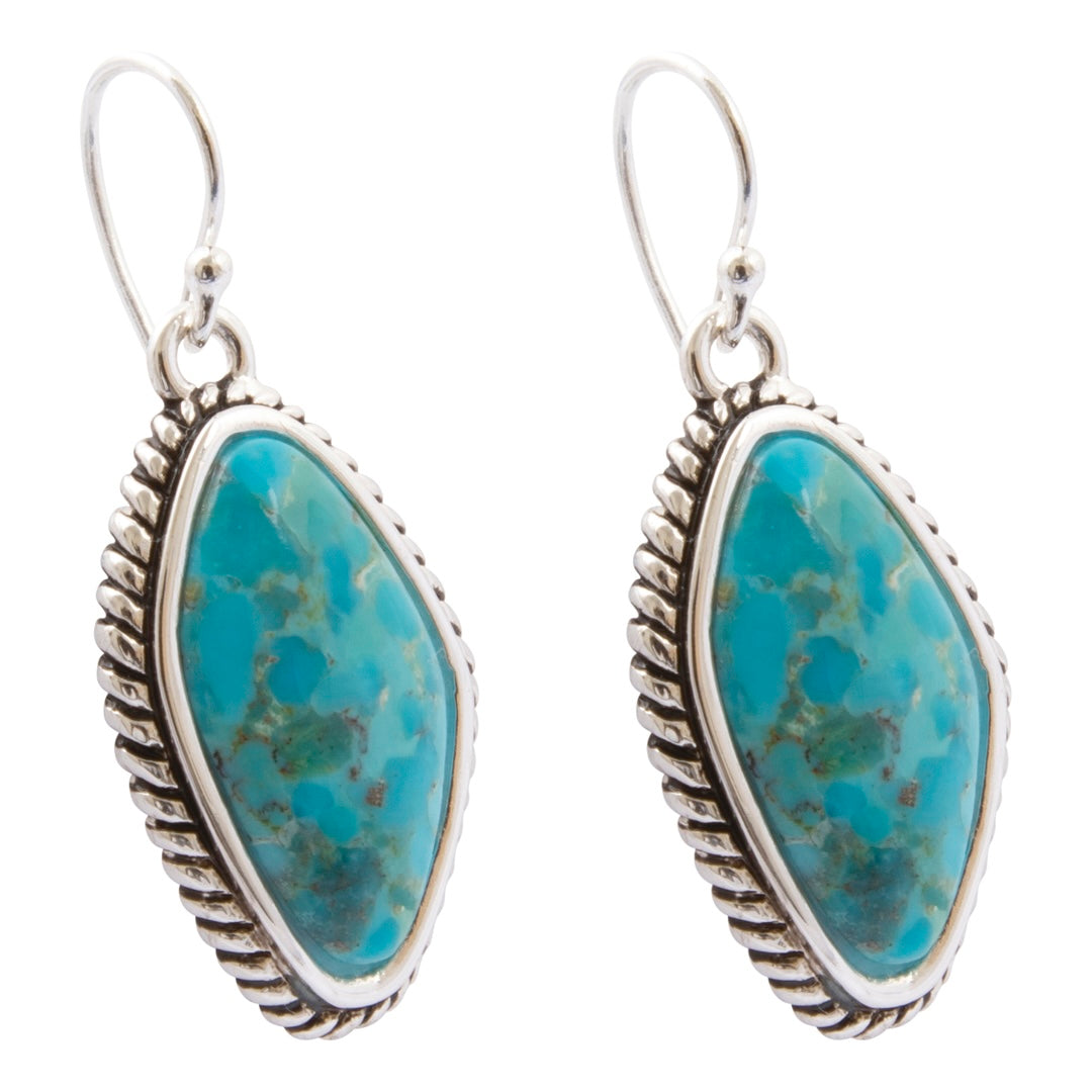 A pair of silver drop earrings featuring oval turquoise stones with natural matrix patterns, set in a textured bezel with a rope border and silver fishhook wires.