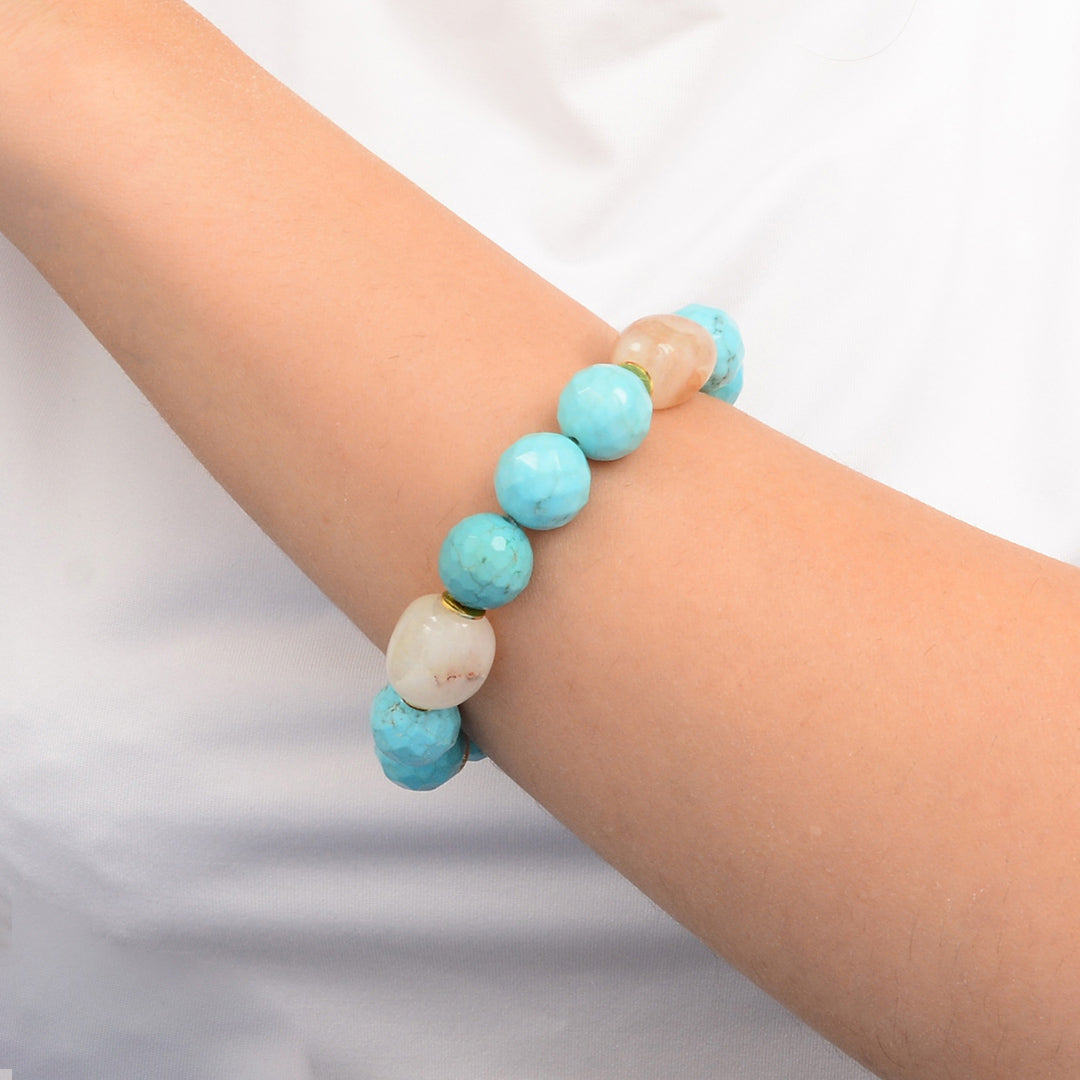 Turquoise and beige beaded bracelet on a wrist against a white background