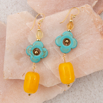 Pair of earrings with turquoise and yellow beads on a stone surface