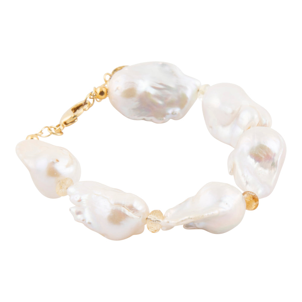 A baroque pearl bracelet with irregular white pearls separated by small gold spacer beads and a gold clasp, shown on a plain white background.