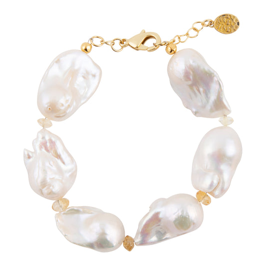 A baroque pearl bracelet with irregular white pearls and small gold spacer beads, connected by a gold chain with a lobster clasp and a round gold brand tag.