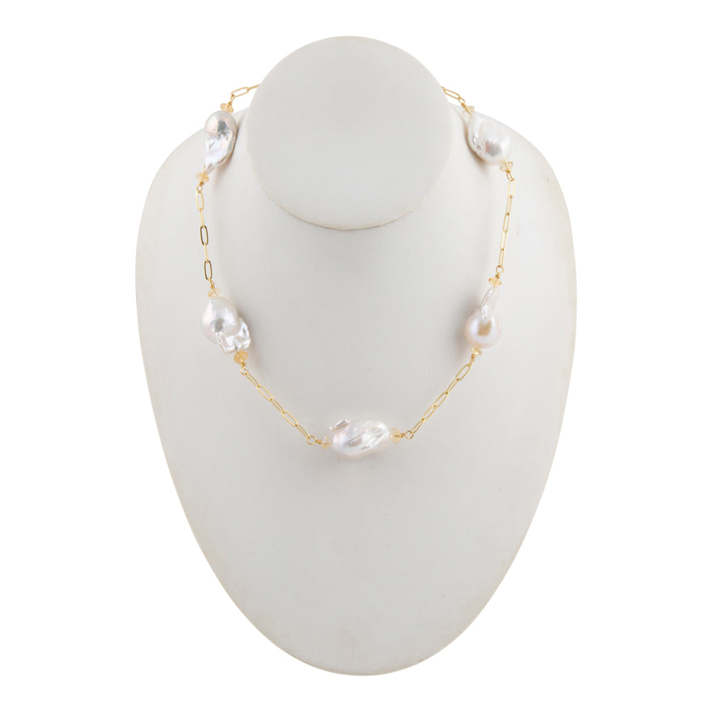 A delicate gold chain necklace with irregular white baroque pearls, displayed on a white mannequin bust against a plain white background.