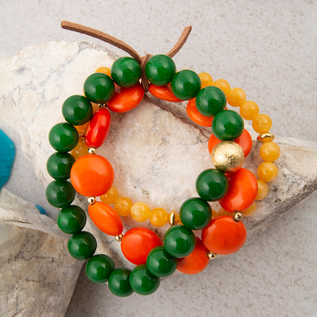 Colorful beaded bracelet with green, orange, and yellow beads on a stone surface