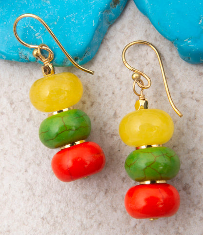 Colorful beaded earrings with gold hooks on a textured surface.
