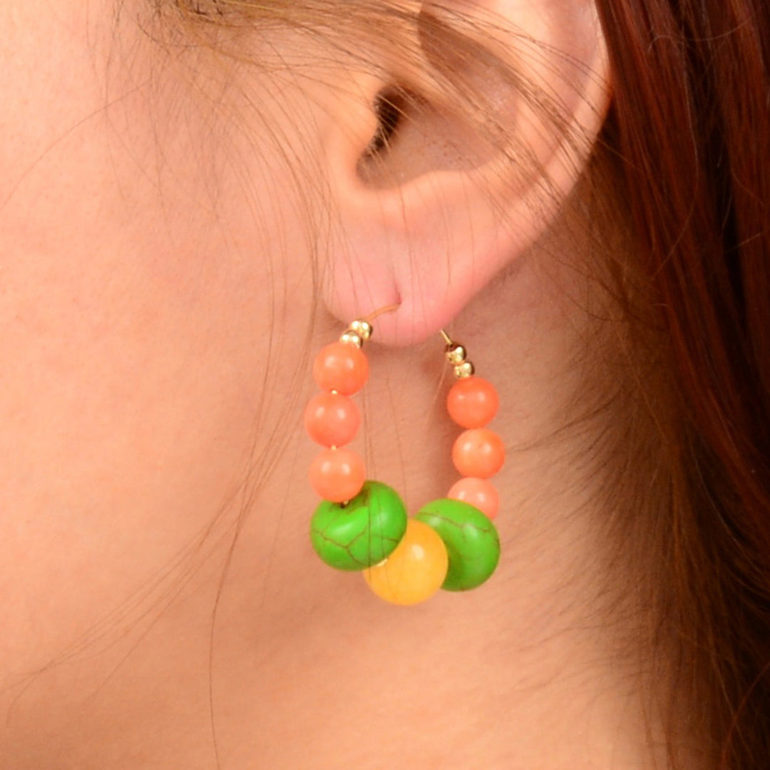 Close-up of a person wearing colorful beaded hoop earrings.