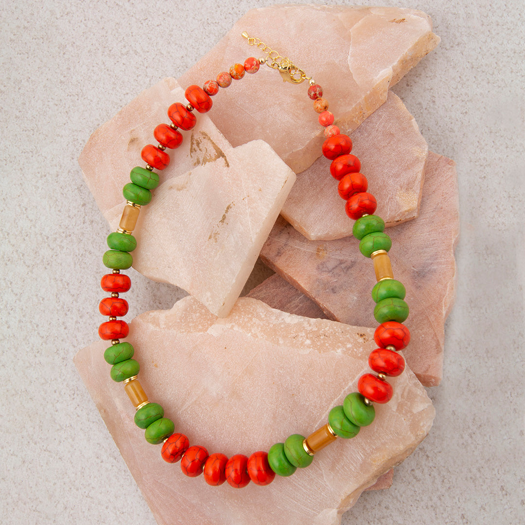 Necklace with green, red, and brown beads on a textured background