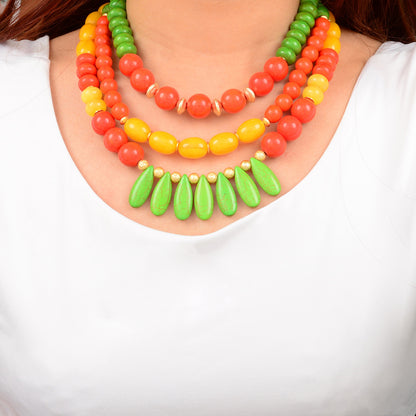 Colorful beaded necklace with green teardrop pendants on a white background