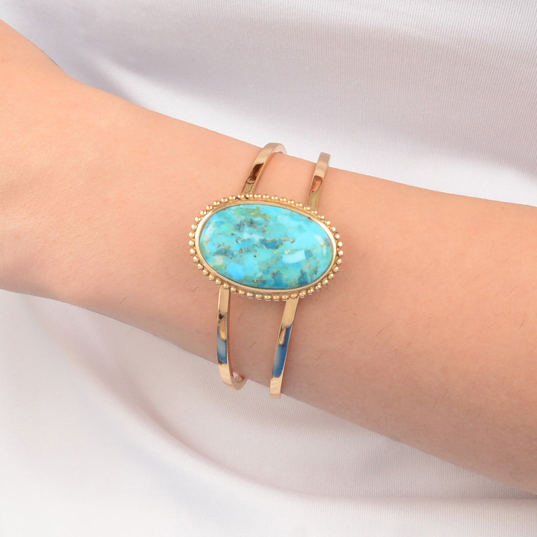 Turquoise stone bracelet on a person's wrist against a white background