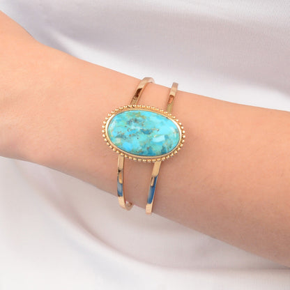 Turquoise stone bracelet on a person's wrist against a white background