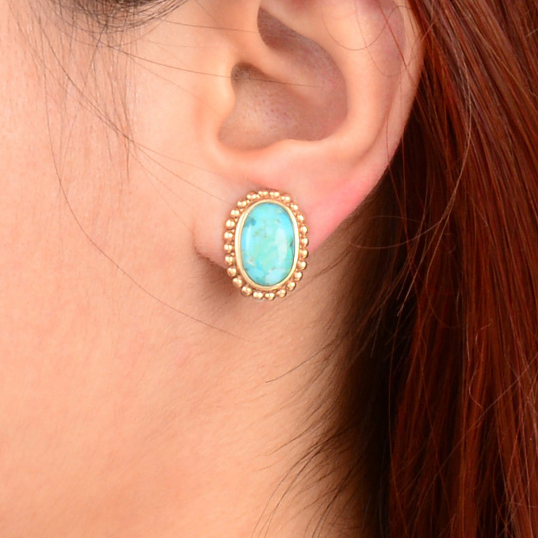Turquoise earring on a person's ear with gold detailing