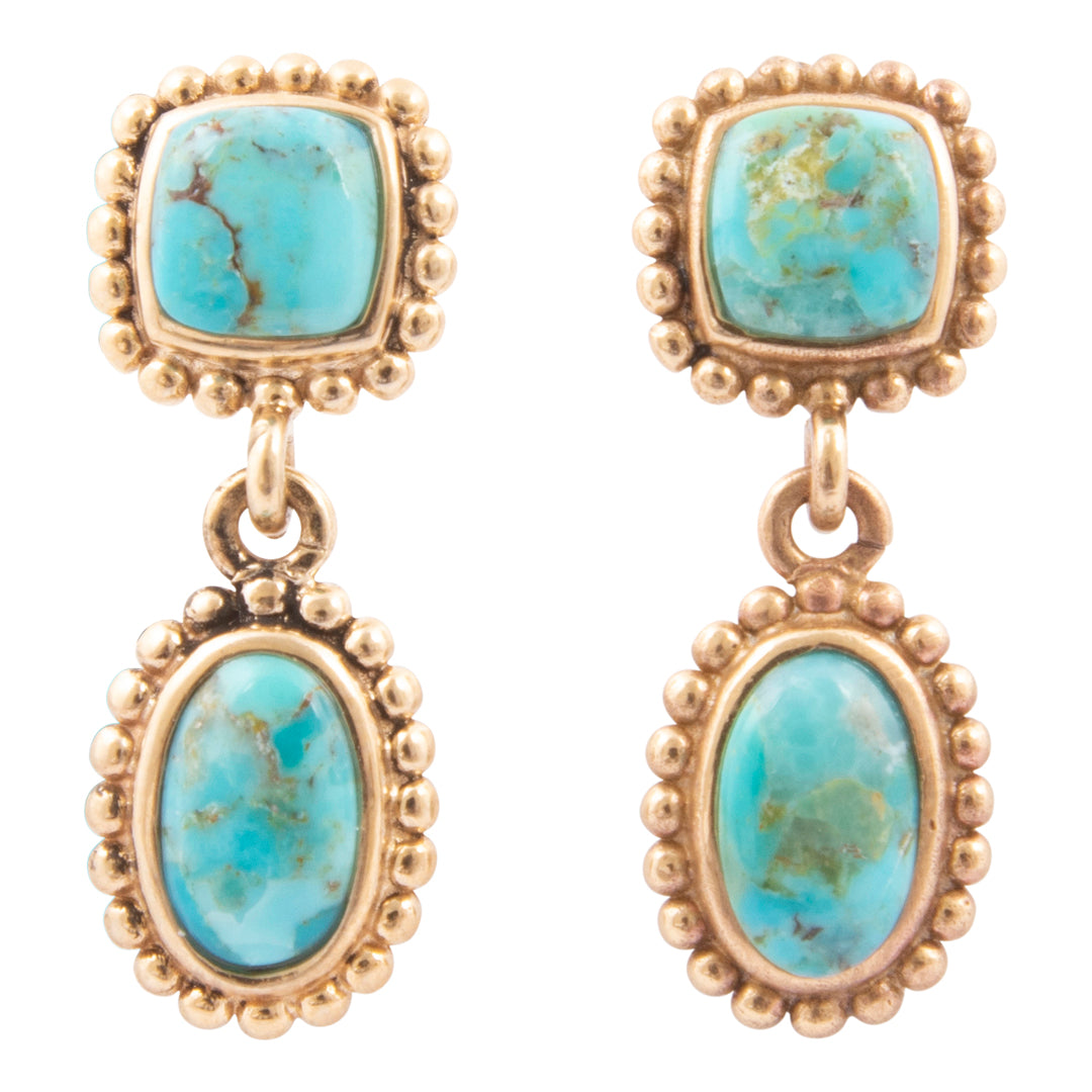 Pair of earrings with turquoise stones and gold frames on a white background