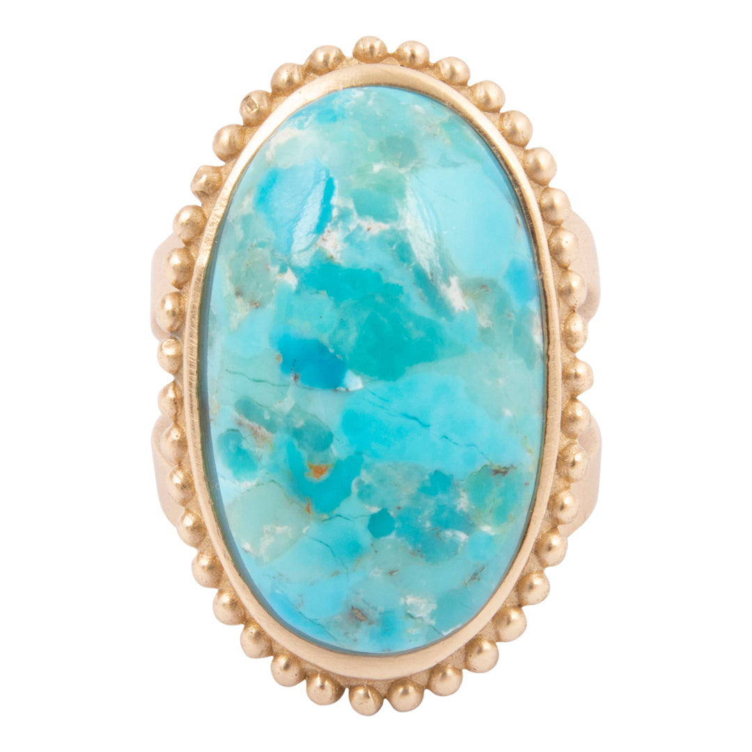 Ring with a large turquoise stone and gold band on a white background