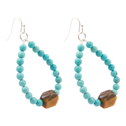 A pair of dangling earrings made of small turquoise-blue beads forming an open teardrop shape, with a faceted brown tiger's eye stone at the bottom and silver fishhook ear wires, shown on a plain white background.