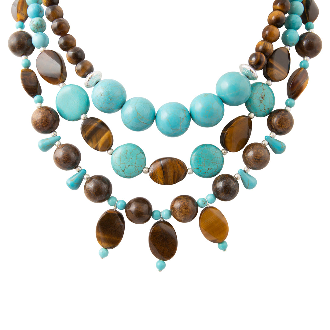 A multi-strand statement necklace featuring turquoise blue beads, brown tiger's eye beads, and polished dark brown beads, accented with small turquoise spacers, shown on a plain white background.