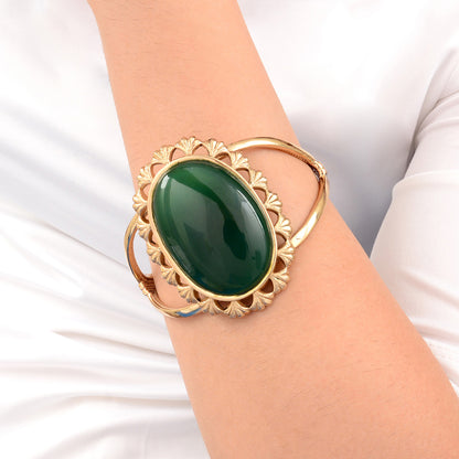 Gold bracelet with a green stone on a white background