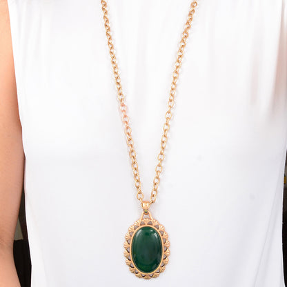 Gold necklace with a green pendant on a white background
