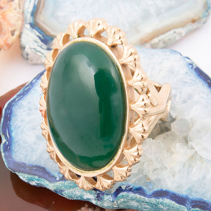 Gold ring with a green stone on a textured surface