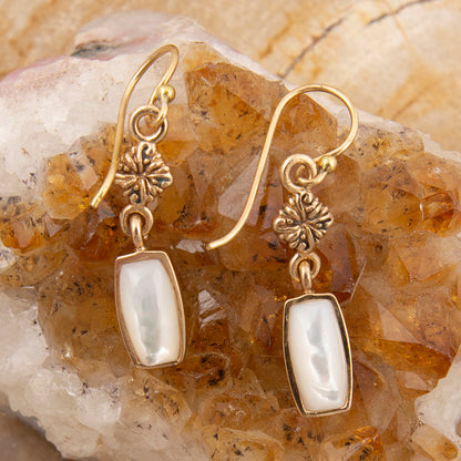 Gold earrings with white stones on a stone background