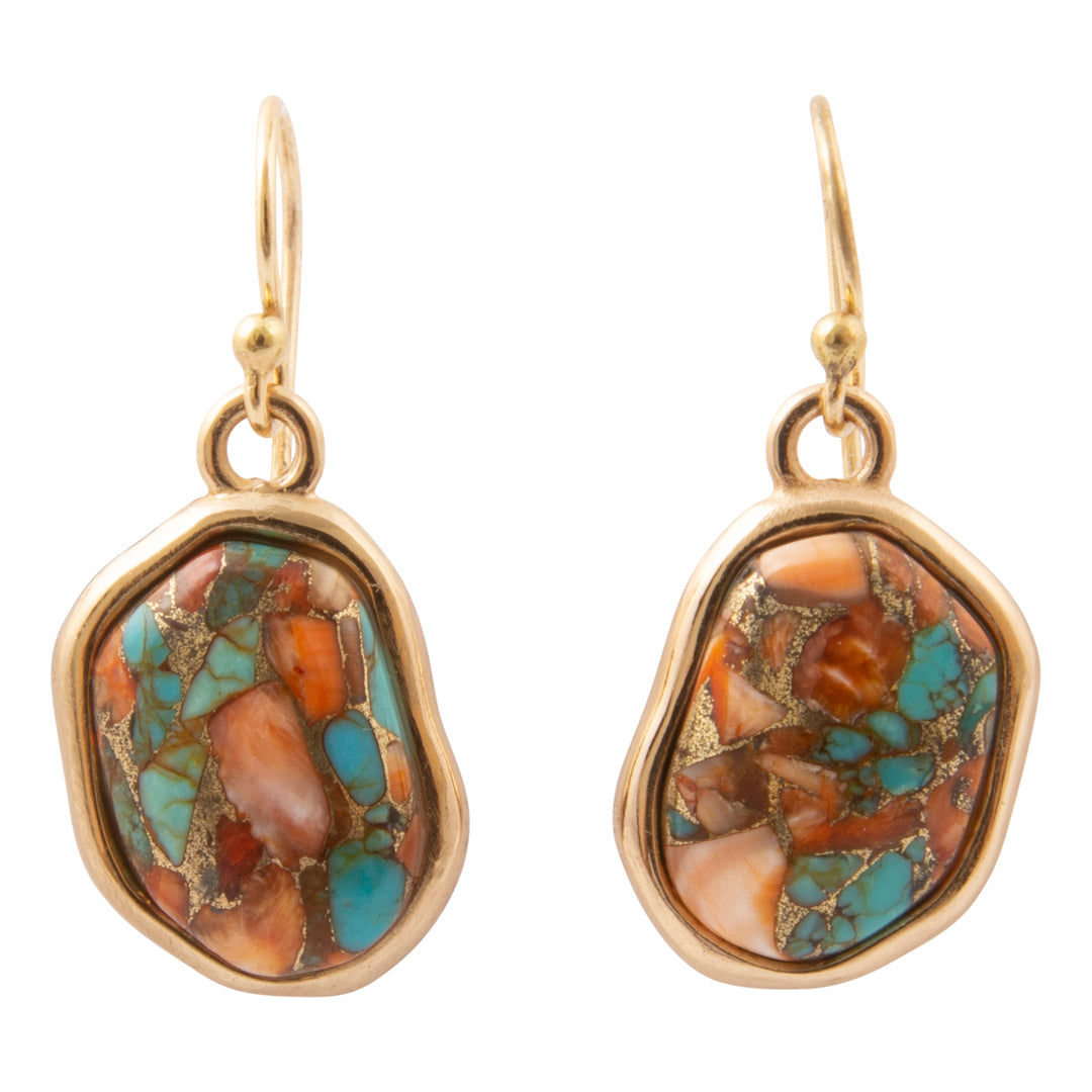 A pair of gold drop earrings featuring irregular, organic-shaped turquoise and orange stone inlays, set in a polished gold bezel with gold leaf accents, on a solid white background.