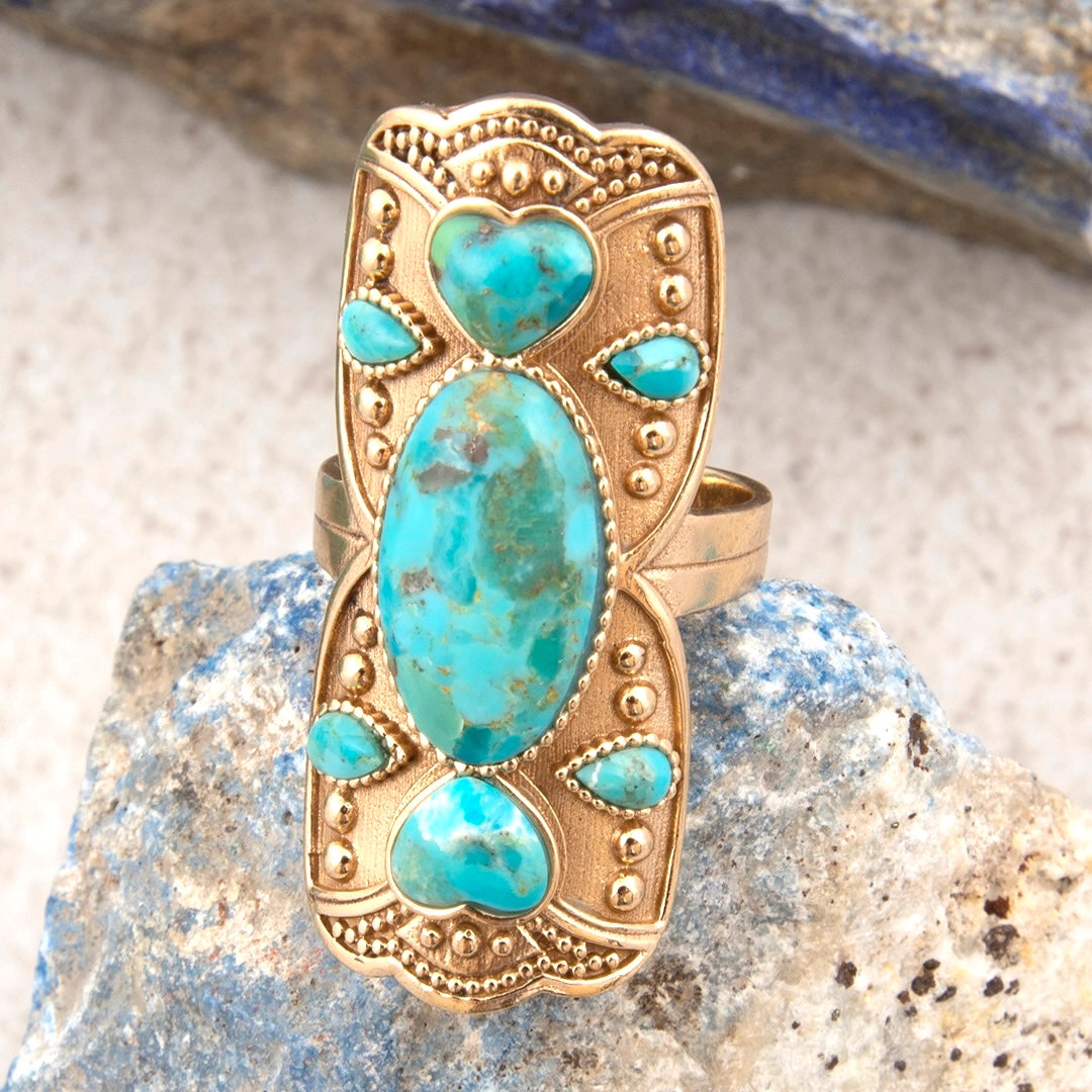 Gold ring with turquoise stones on a stone background