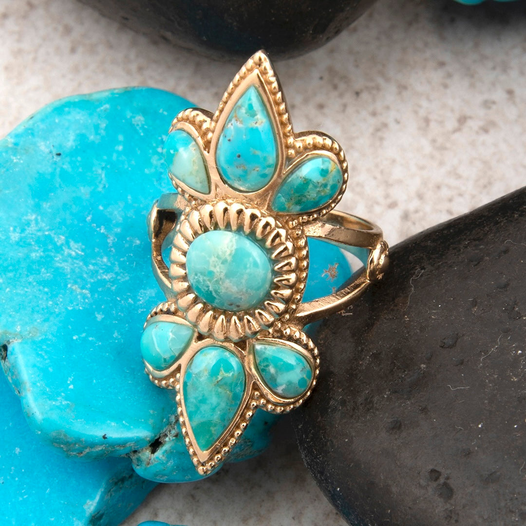 Gold ring with turquoise stones on a stone background