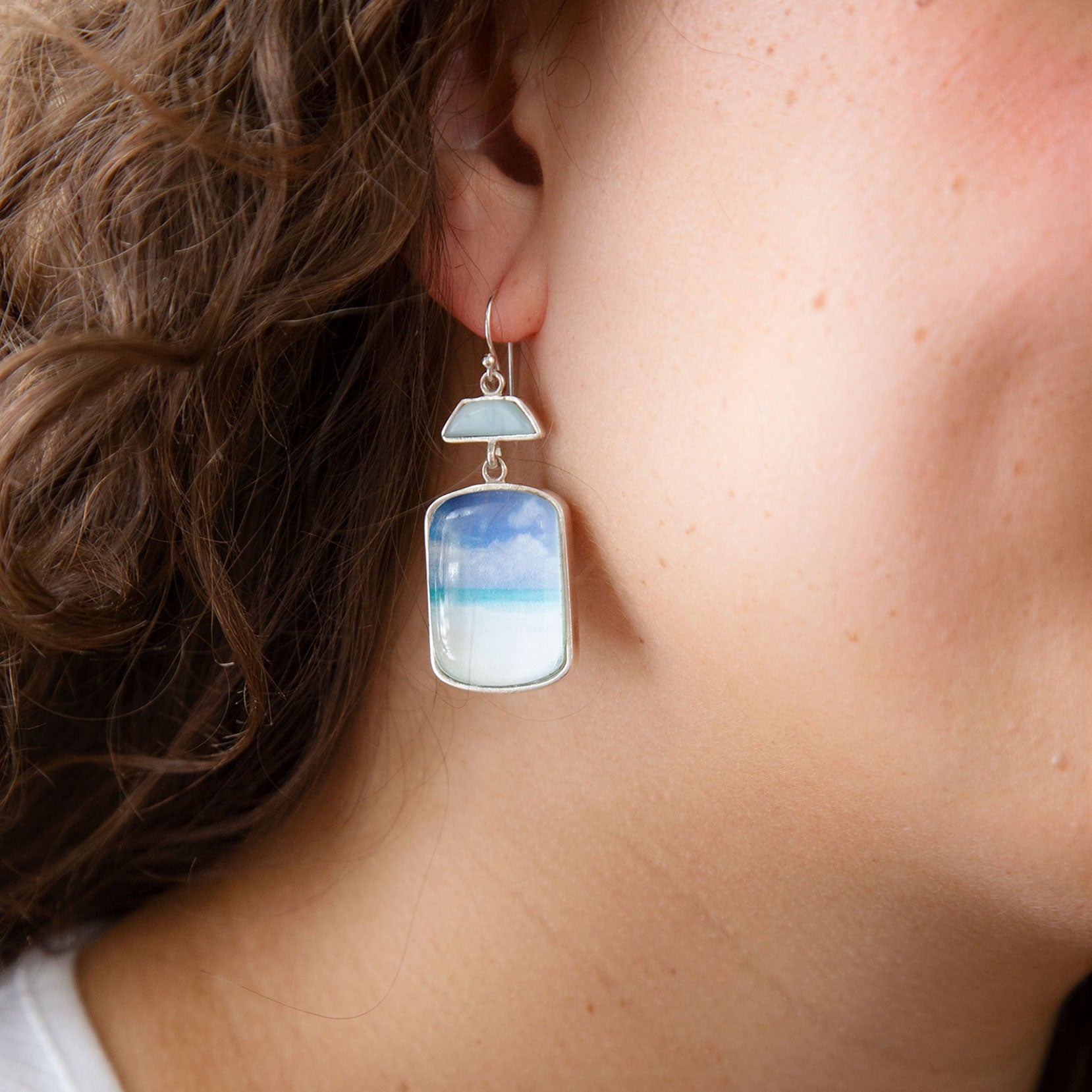 Earring with a gradient design worn by a person against a blue background