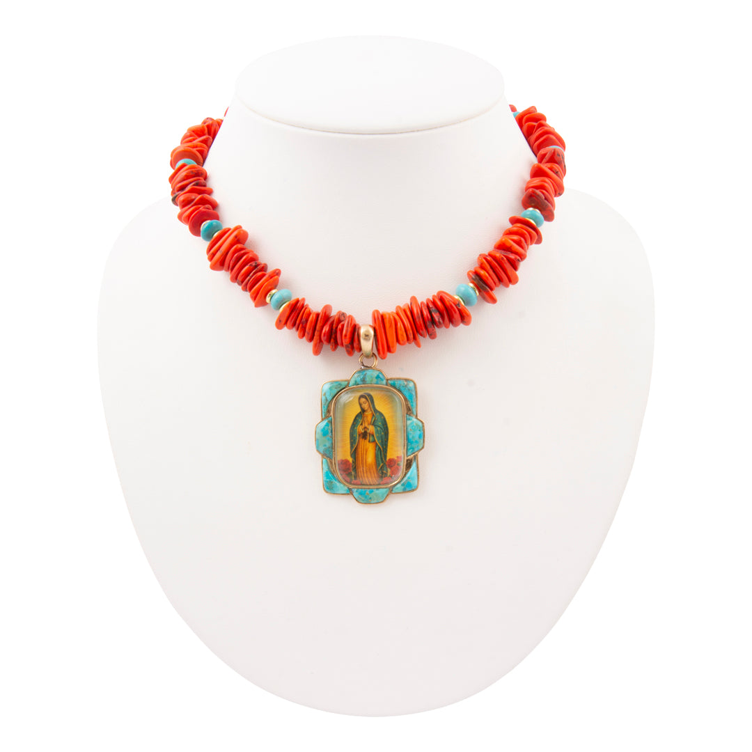 Necklace with red beads and a central pendant on a white stand