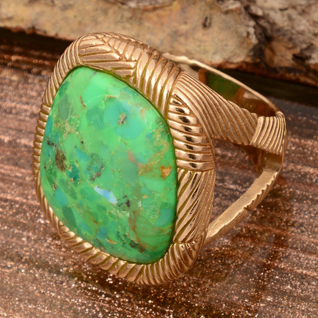 Gold ring with a large green stone on a wooden surface